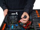 Mężczyzna w czarnym ubraniu montuje podzespoły komputera w obudowie PC